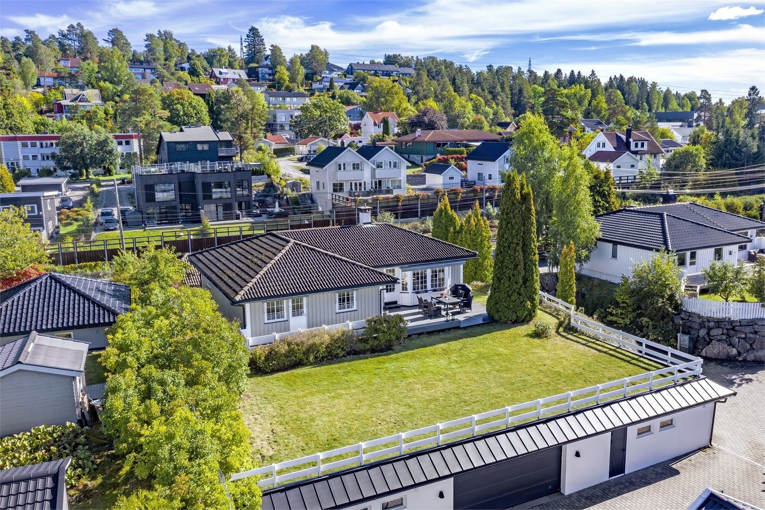 Tomten er pent opparbeidet med blant annet stor hage, diverse beplantninger og solrik platting