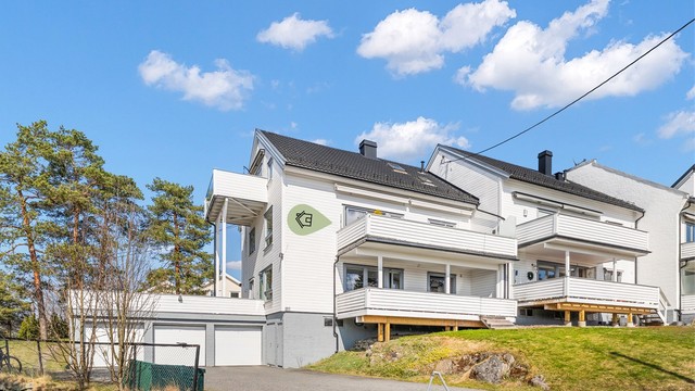 Det medfølger garasjeplass på ca. 16 kvm i felles garasjerekke, utstyrt med elbillader. Leiligheten disponerer også en utvendig parkeringsplass. Tomten er pent opparbeidet med plenarealer og asfalterte adkomstveier.