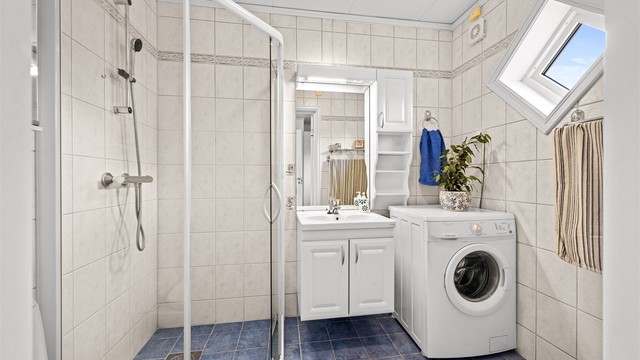 Flislagt bad med vannbåren gulvvarme, dusjnisje med glassdør og opplegg for vaskemaskin.