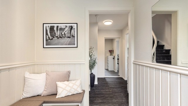 Praktisk sittebenk i entréen og åpen sikt videre inn mot gangen og oppholdsrommene.