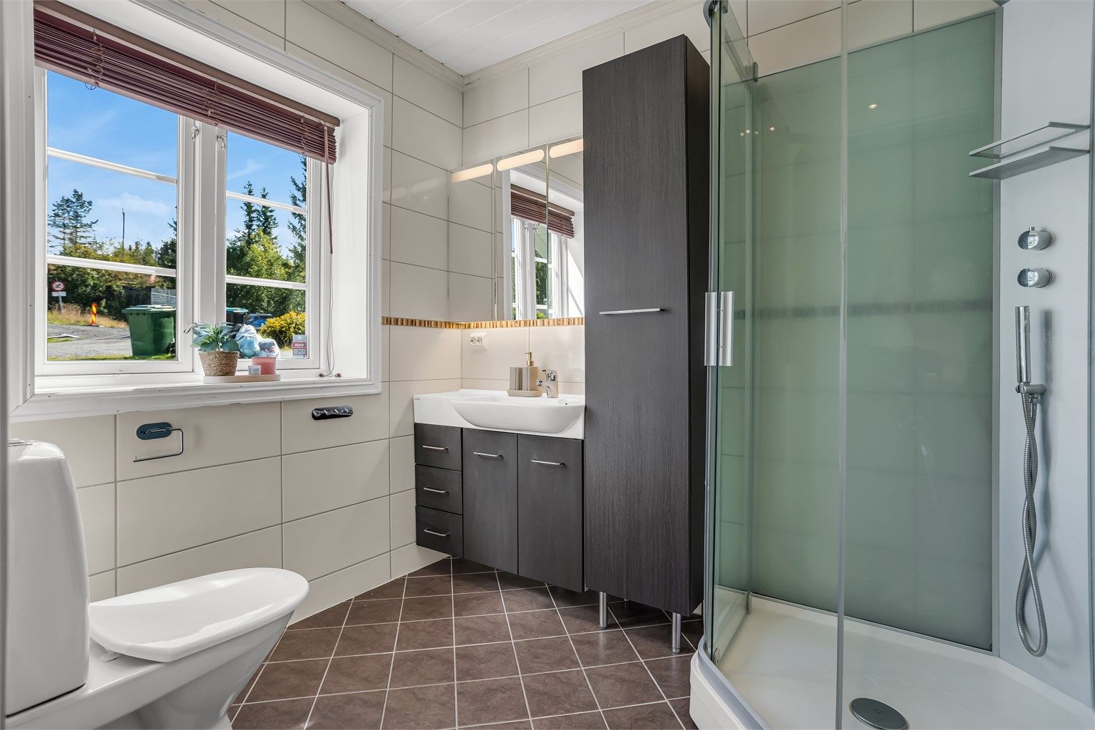 Flislagt bad, med gulvvarme. Badet er videre bestående av servant innredning, speilskap, gulvstående toalett og dusjkabinett. 
Videre fra badet finner du vaskerom - med opplegg for vaskemaskin. 