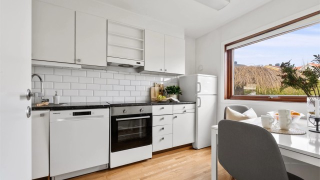 På kjøkken er det bra med skapplass, skuffer- og benkeplass, samt stort vindu, som gir lysinnslipp og utsikt mot inngangsparti.