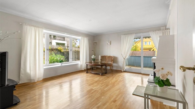 Romslig stue i andre etasje med murt peis og direkte utgang til balkong.