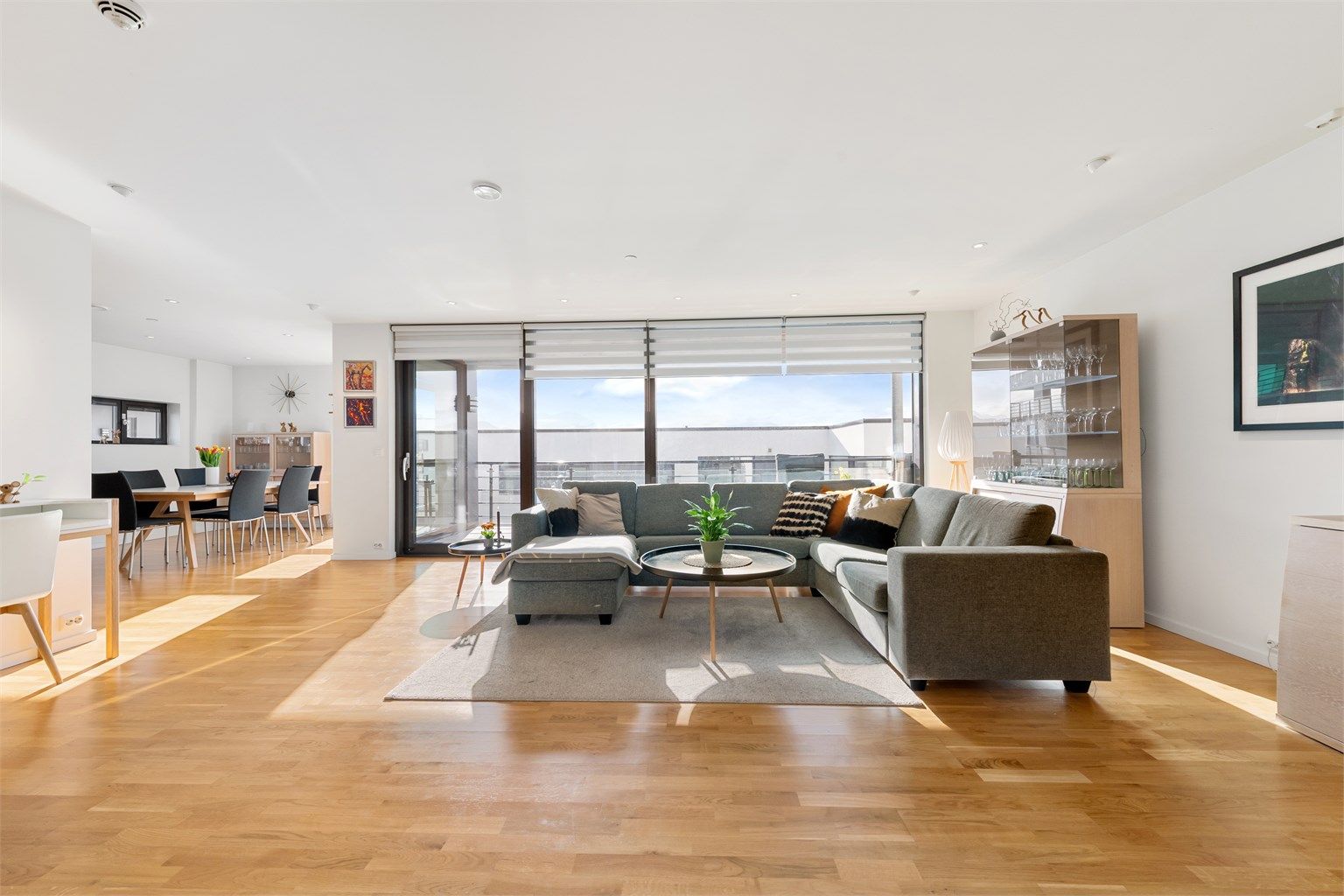 God plass i stuen som har lyse overflater og store vindusflater mot syd  