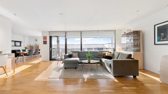 God plass i stuen som har lyse overflater og store vindusflater mot syd