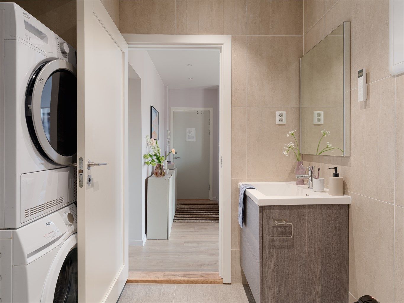 Badet har vegghengt toalett og et praktisk opplegg for vaskesøyle bak døra.