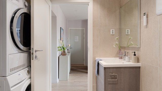 Badet har vegghengt toalett og et praktisk opplegg for vaskesøyle bak døra.