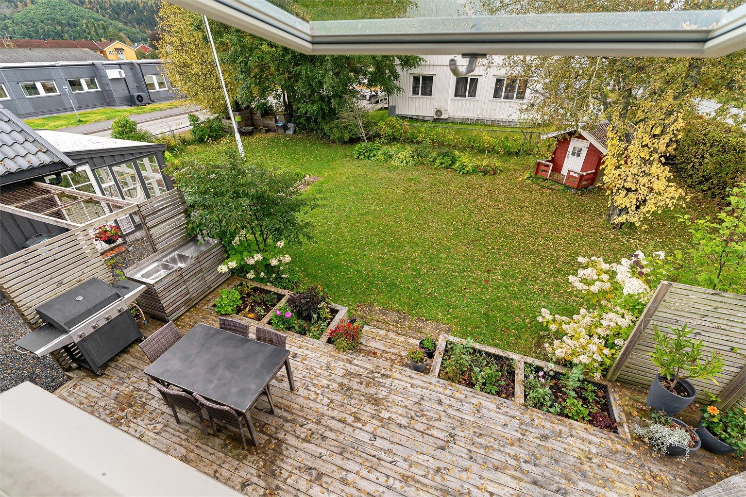 Terrasse på bakkeplan i trekonstruksjon med utekjøkkenbenk og god plass til utemøbler.