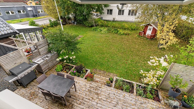 Terrasse på bakkeplan i trekonstruksjon med utekjøkkenbenk og god plass til utemøbler.