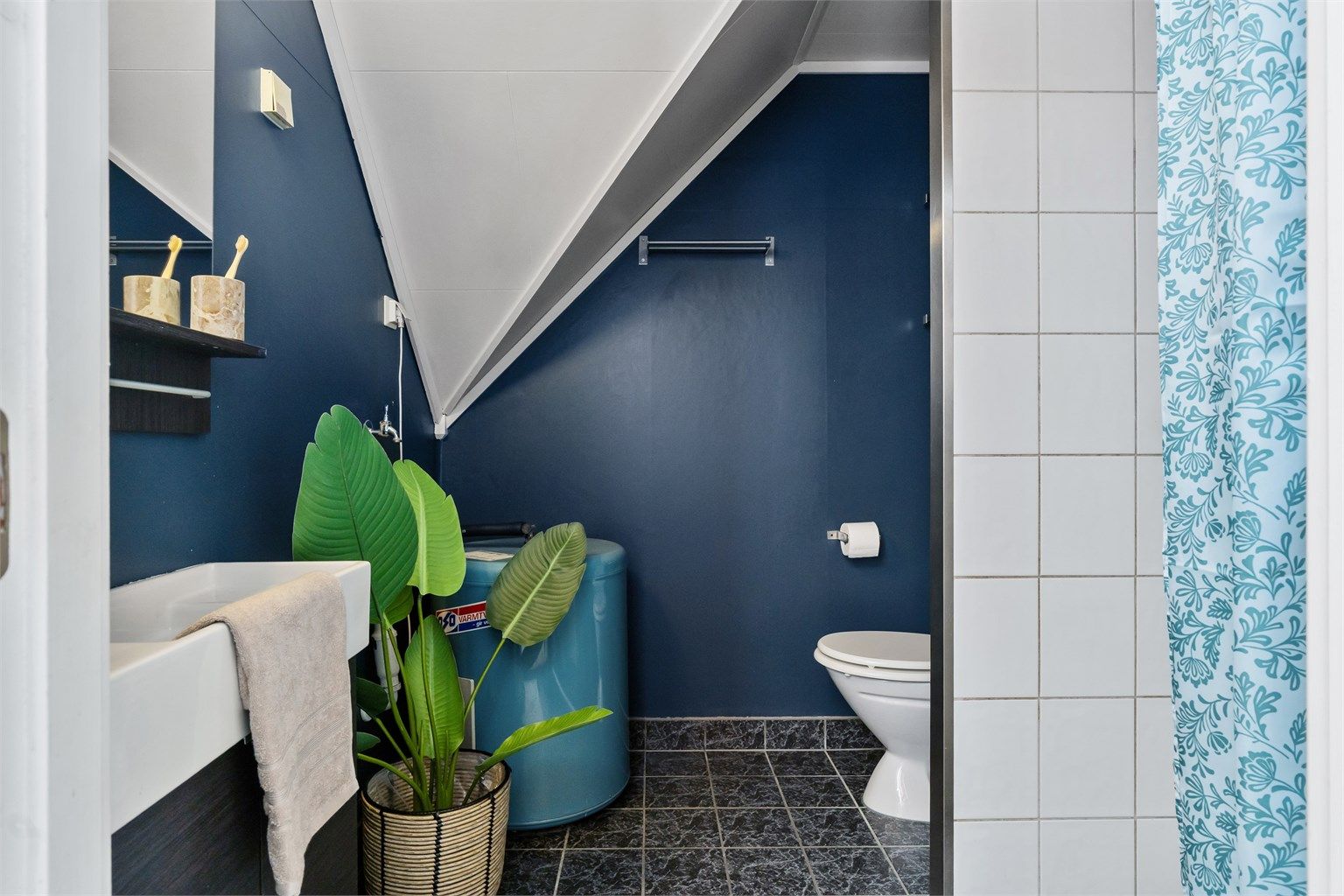 Badet er innredet med servantseksjon, gulvstående toalett og varmtvannsbereder.