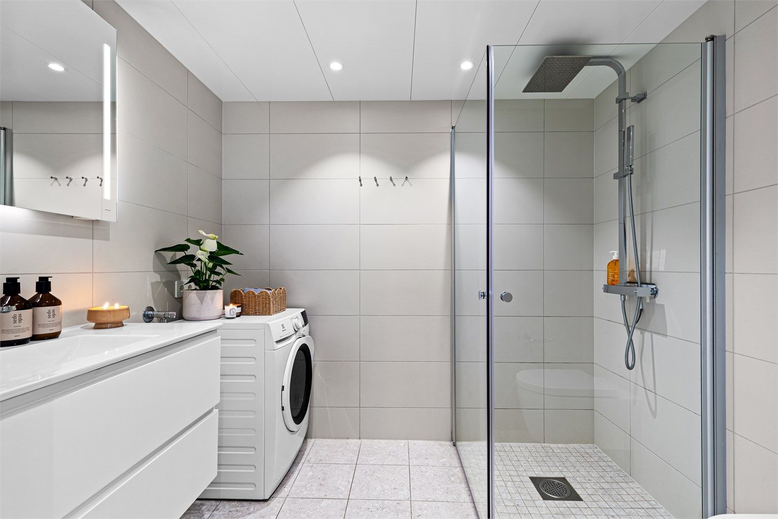 Badet har delikate og moderne fliser samt kombinert hånd/regnfallsdusj og praktiske knagger 