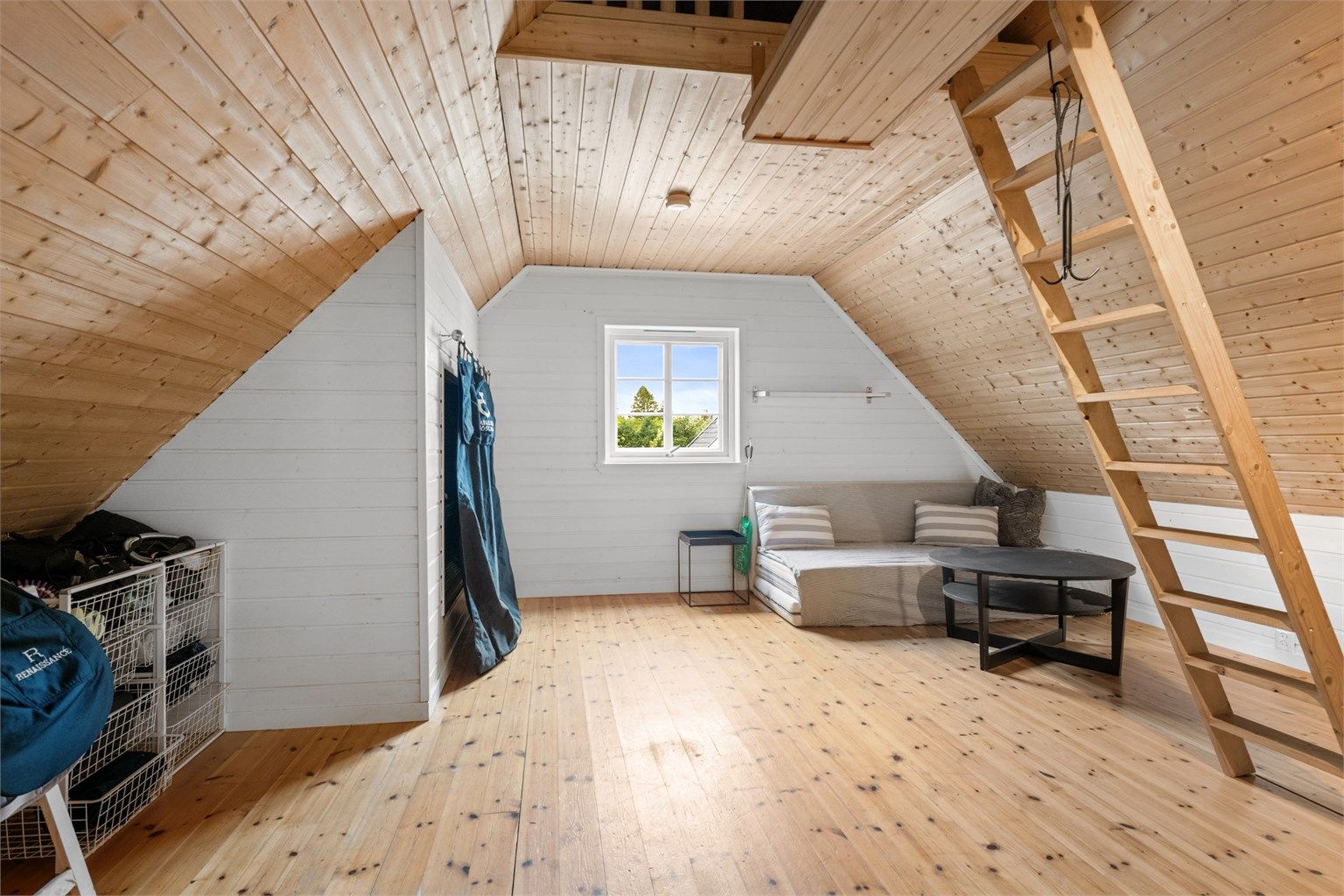 Det innredede rommet over garasjen har trepanel på vegger og i tak.