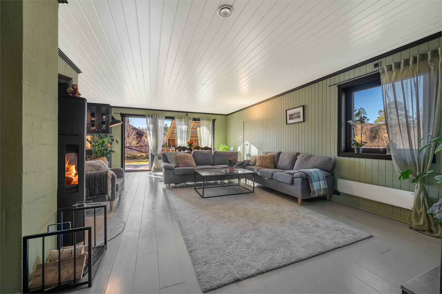 Lys og trivelig stue med peisovn og utgang til solrik terrasse og hage.