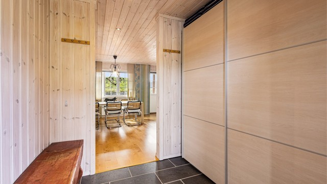 Romslig entré med skyvedørsgarderobe og åpen passasje videre inn til oppholdsrommene.