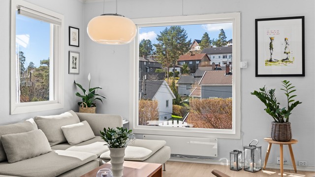 Vinduene i stuen rammer inn utsikten over det etablerte nabolaget.