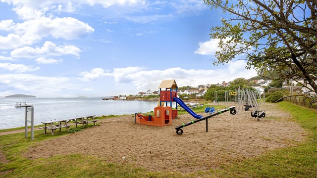 Barnevennlig strand med lekeplass og sittebenker i nærområdet.