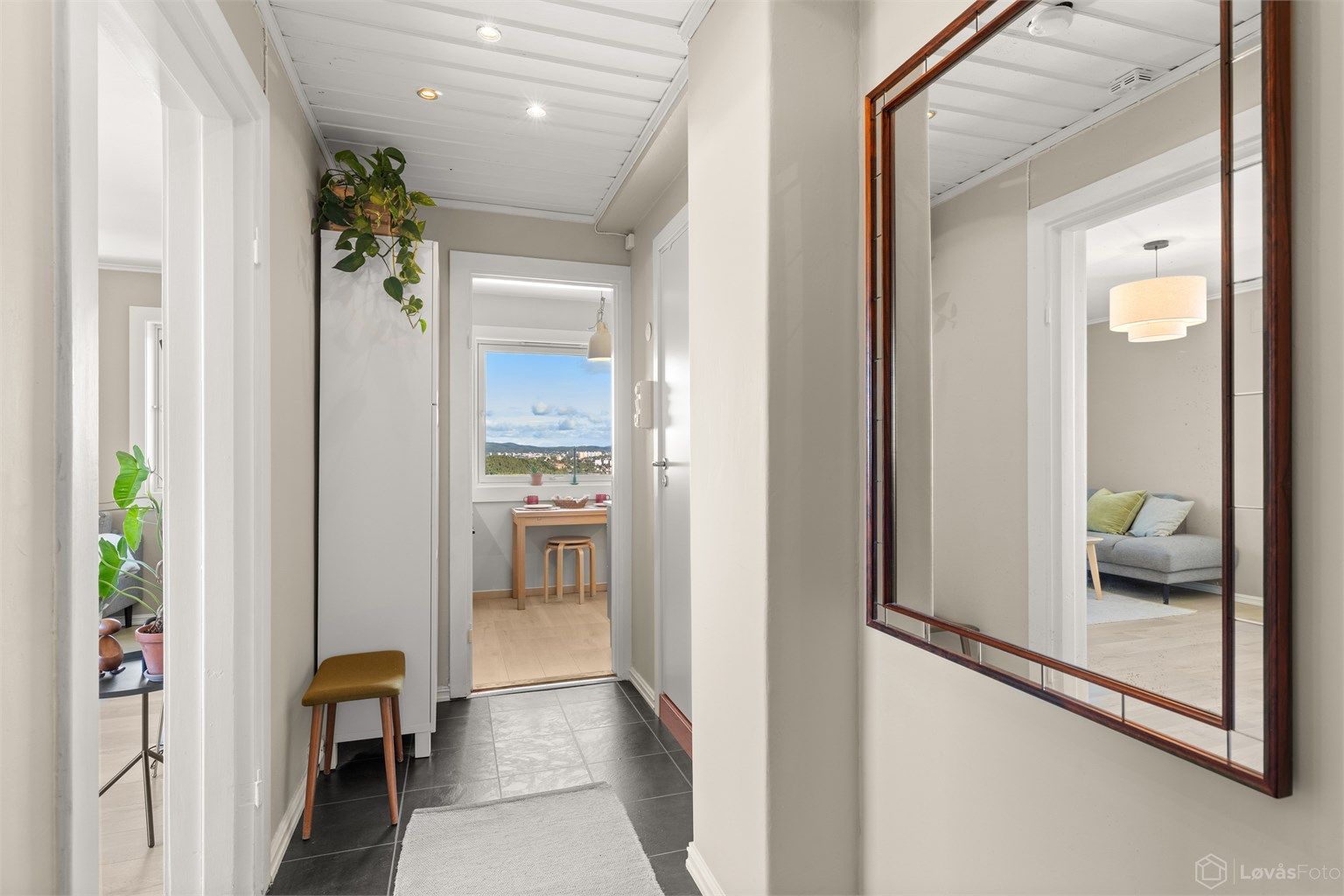 En lys og innbydende entré med moderne overflater, downlights og garderobeskap. Entréen fungerer samtidig som et naturlig og funksjonelt bindeledd mellom boligens øvrige rom.
