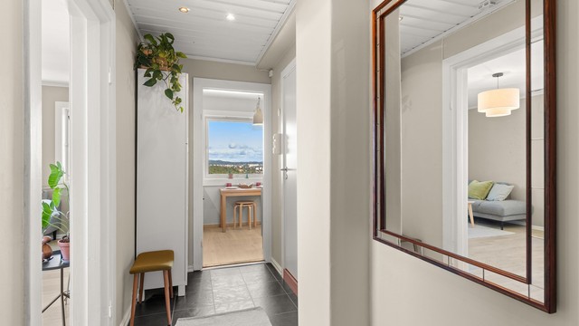 En lys og innbydende entré med moderne overflater, downlights og garderobeskap. Entréen fungerer samtidig som et naturlig og funksjonelt bindeledd mellom boligens øvrige rom.