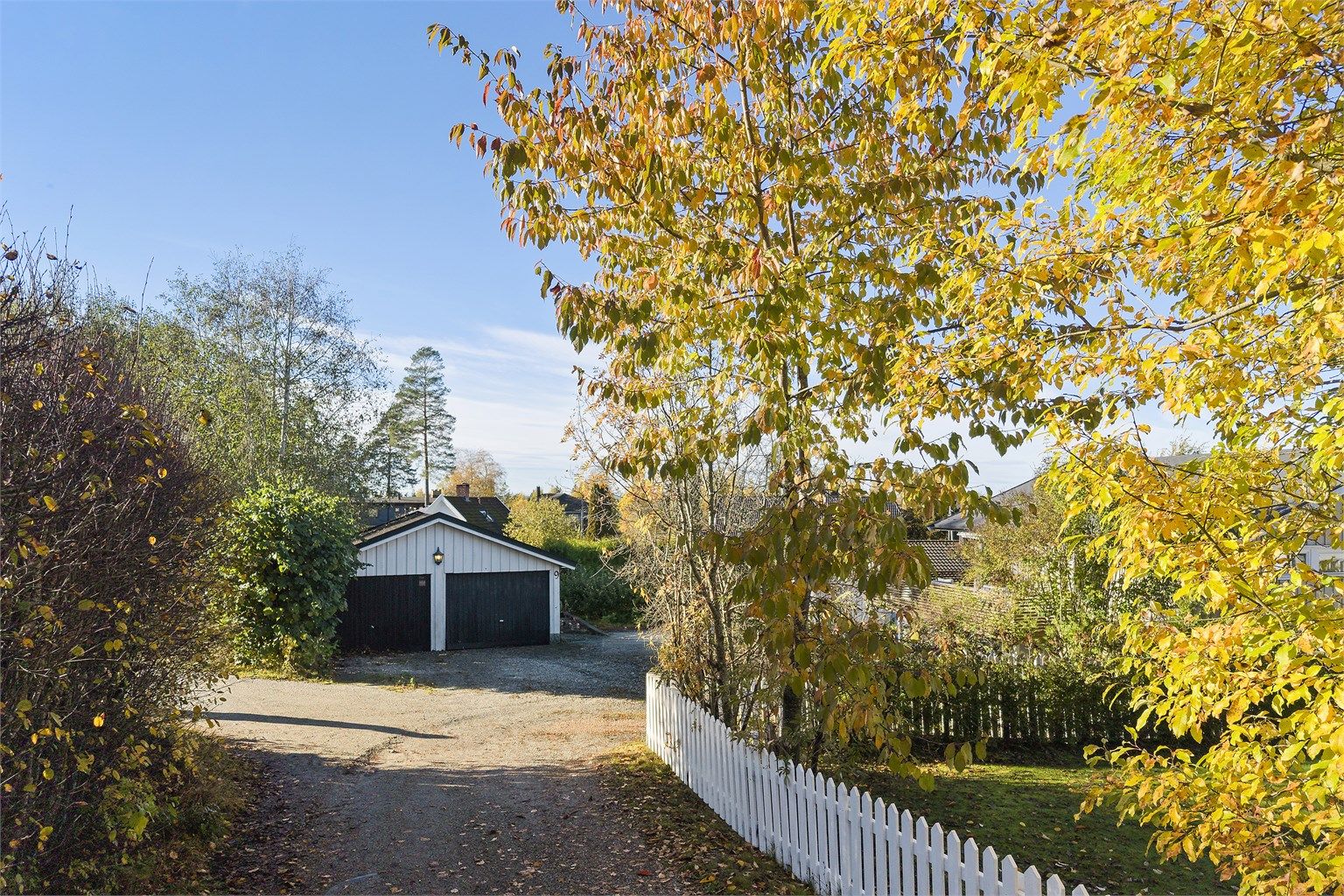 Innkjøring til eiendommen med parkering foran dobbelgarasjen.