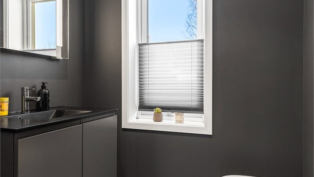 Toalettrom med fliser på gulv med gulvvarme. Malte veggflater. Nedsenket himling med downlights. Vegghengt servantinnredning. Ovenpåliggende servant med armatur. Vegghengt toalett.