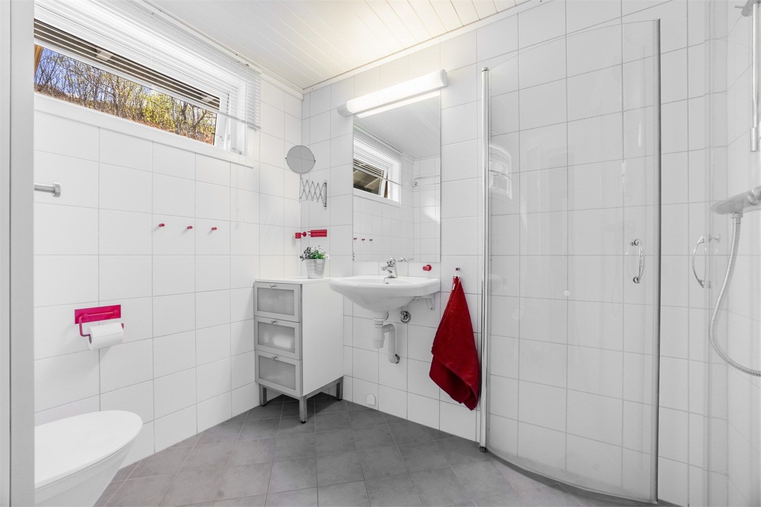 Pent flislagt bad på 4 kvm med servant, speil og lys, toalett og dusjhjørne. 