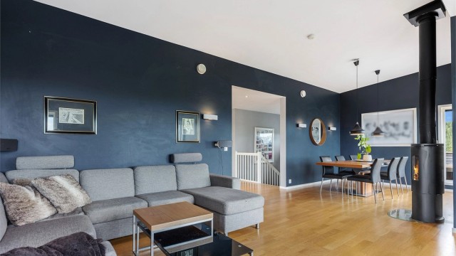 Rommet har god plass til både sofagruppe og spisebord. Peisovnen er strategisk plassert midt mellom.