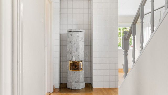 En karakteristisk klebersteinsovn med messingbeslag danner et dekorativt blikkfang.