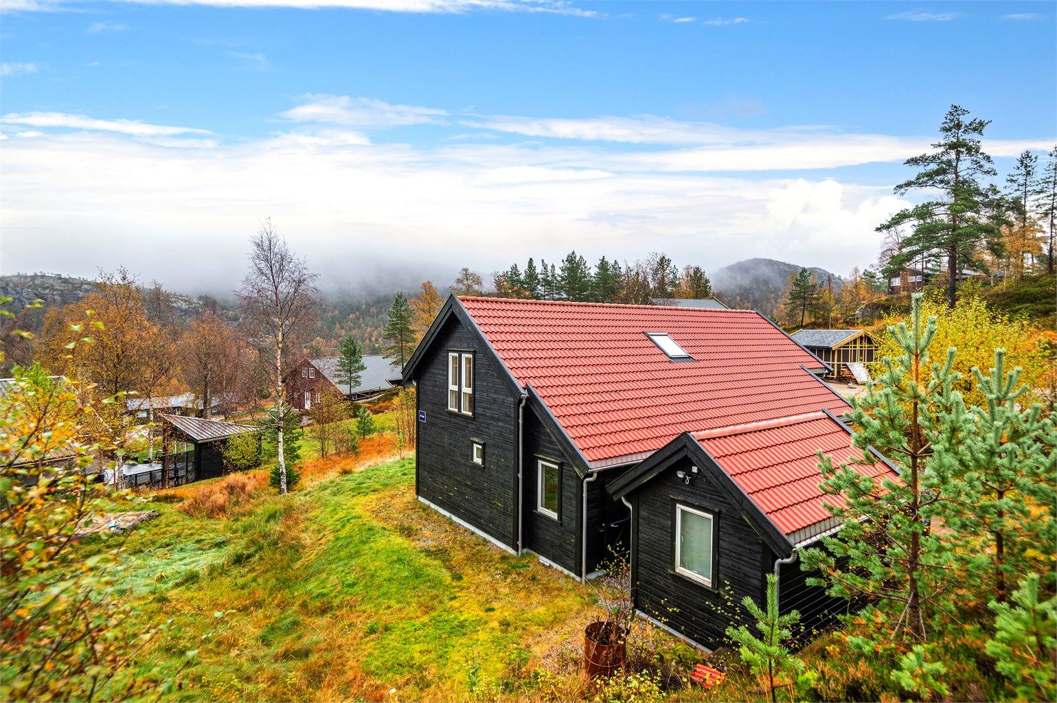 Vakker og naturskjønn beliggenhet, med utsikt over et frodig landskap. Hytten er omgitt av trær og gress, noe som gir en følelse av ro og nærhet til naturen.