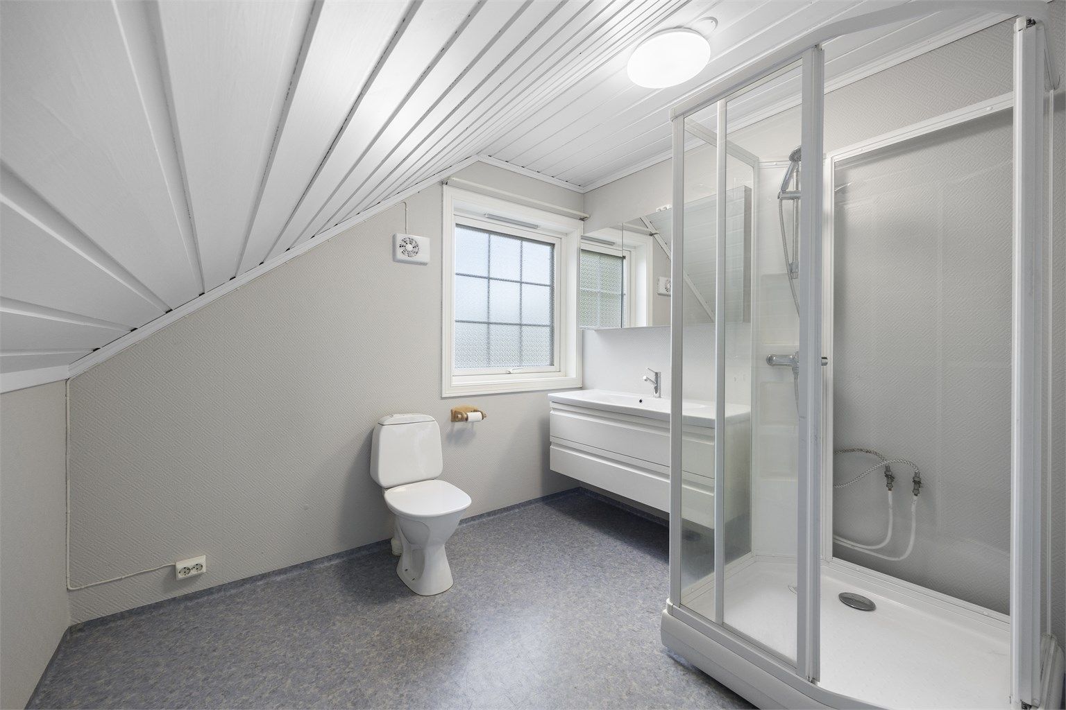 Badet i loftsetasjen er innredet med dusjkabinett, servantinnredning og toalett.