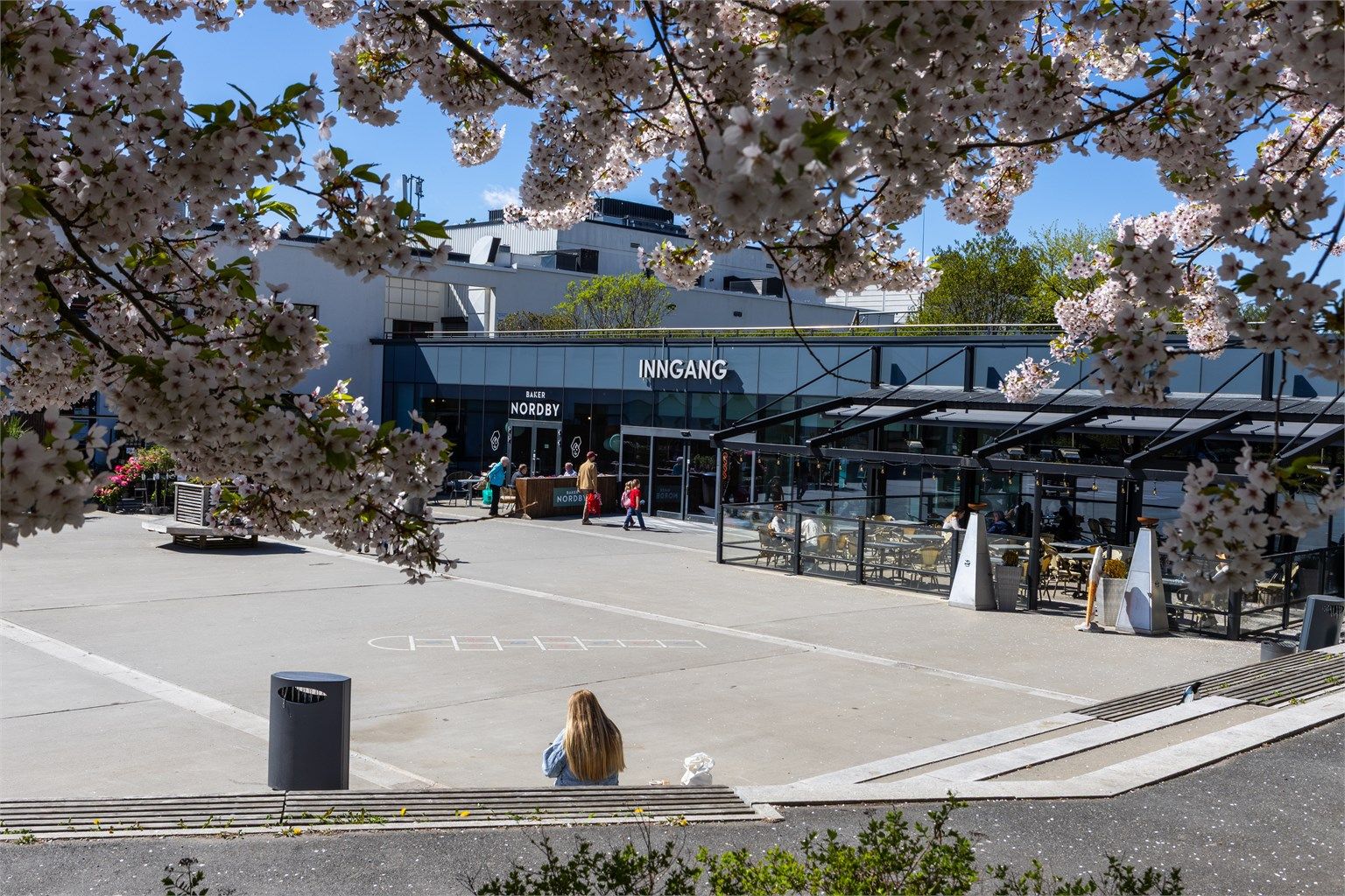 Hyggelig møteplass rett utenfor døren – med innbydende kaféområde, et godt utvalg butikker og et bredt spekter av servicetilbud i nærområdet.