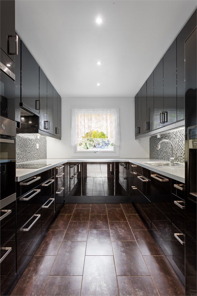 Sort, høyglans kjøkken fra 2011 med delvis integrerte hvitevarer i 1. etasje.