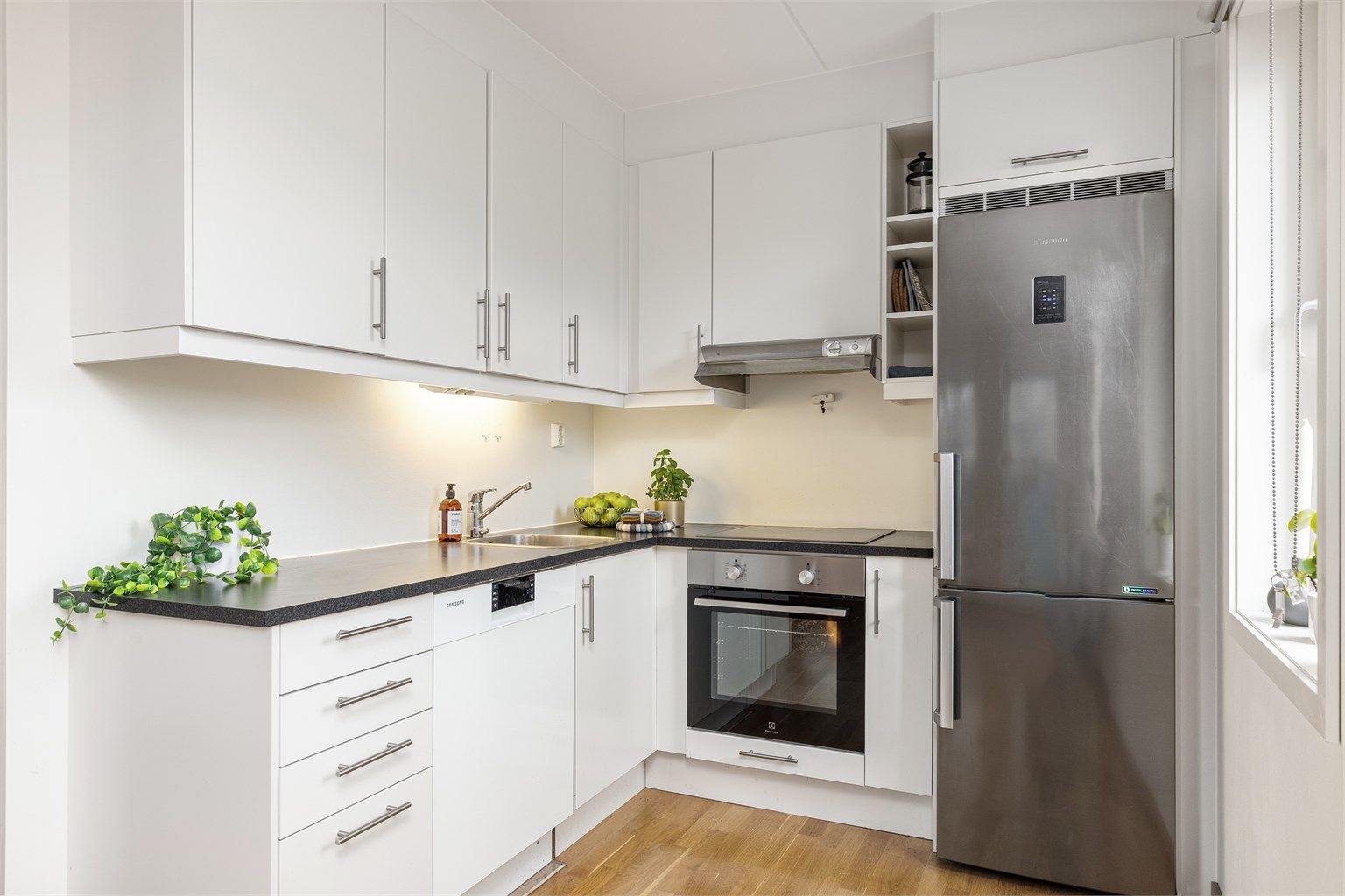 Laminert benkeplate med nedfelt vask, benkebelysning samt integrert stekeovn og platetopp.