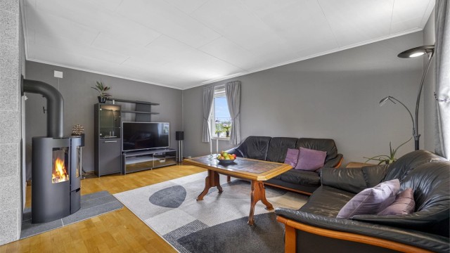 Boligen har en romslig stue med vedovn som gir god varme, og en åpen løsning mot spisestuen.