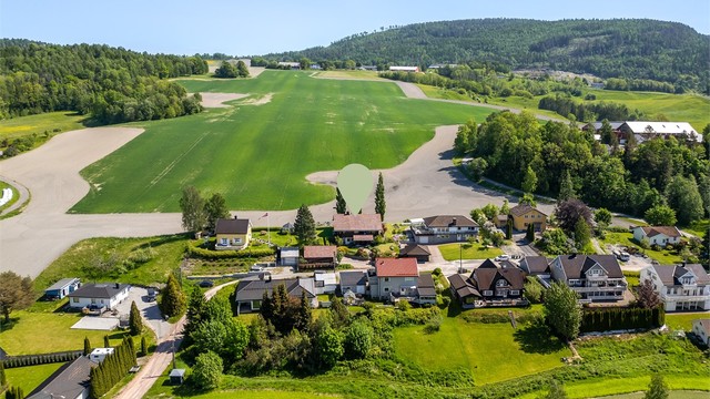 Tilbaketrukket boligfelt som grenser til landbruksarealer i bakkant.