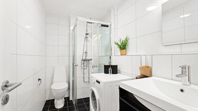 Tidløst baderom som ble modernisert i 2012 antageligvis med flis på eldre overflater. Dusjsone med dusjvegger, toalett, servant med skuffinnredning og vaskemaskin.