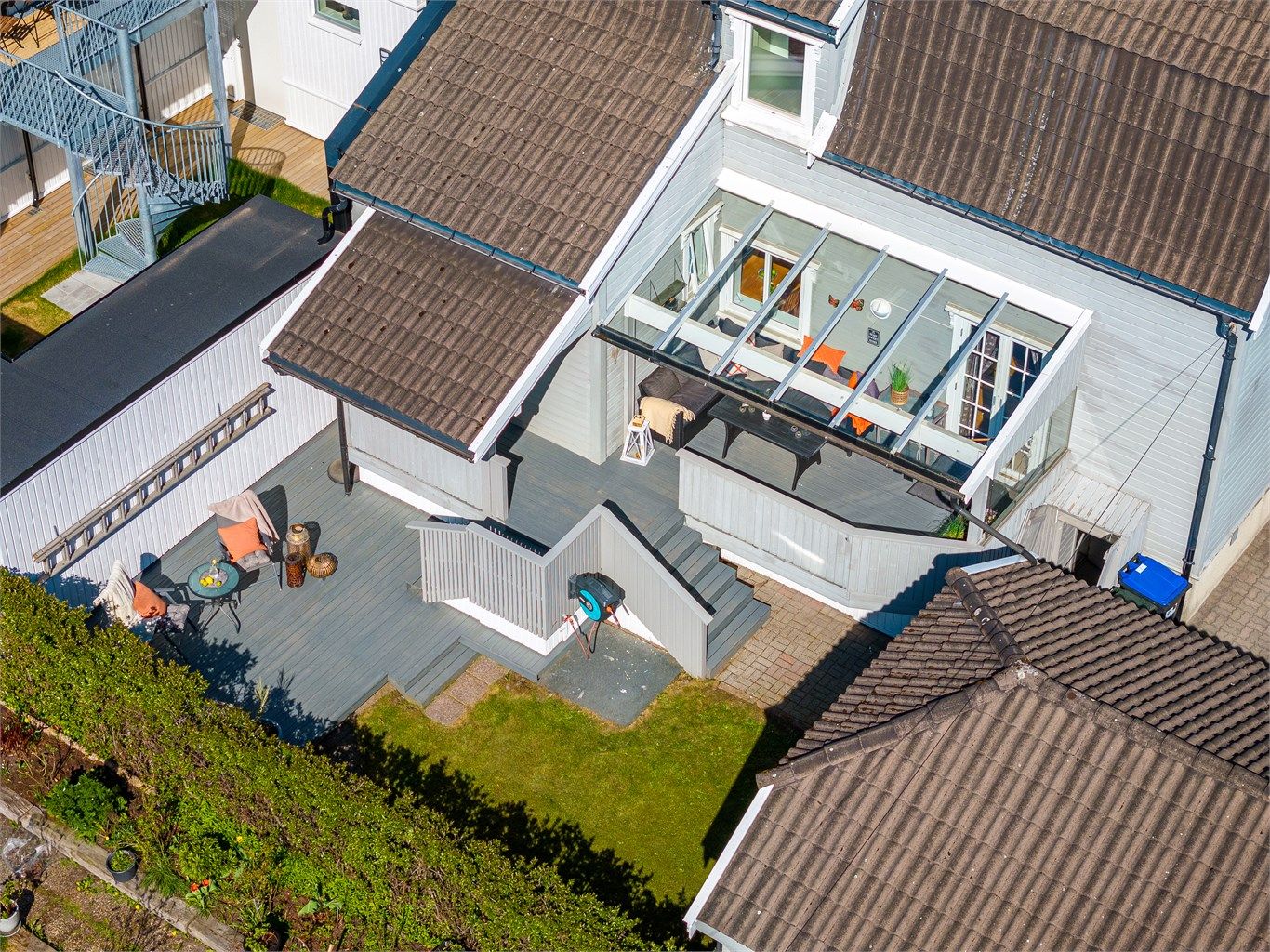 Skjermet bakgårdsidyll med hage og terrasser.