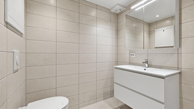 Badet har vegghengt toalett og en moderne servantinnredning.