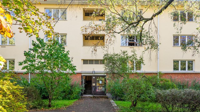 Leilighetens fasade med flotte grøntområder og adkomst via felles trappeoppgang.