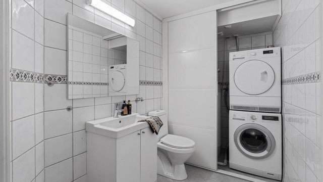 Praktisk gjestetoalett med gulvvarme og en smart vaskeromsløsning bak skyvedør.