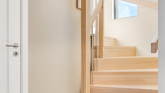 Trappen i heltre eik med stålspiler er et gjennomgående designelement som binder etasjene sammen.