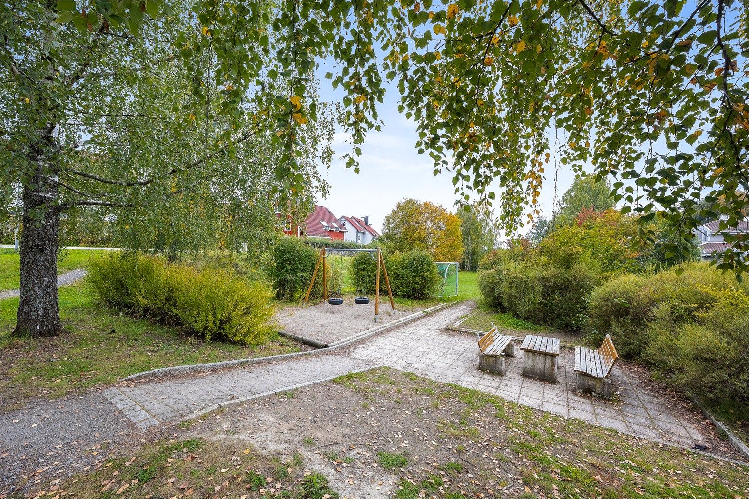 Fellesareal med lekeplass og sittebenker like ved boligen.