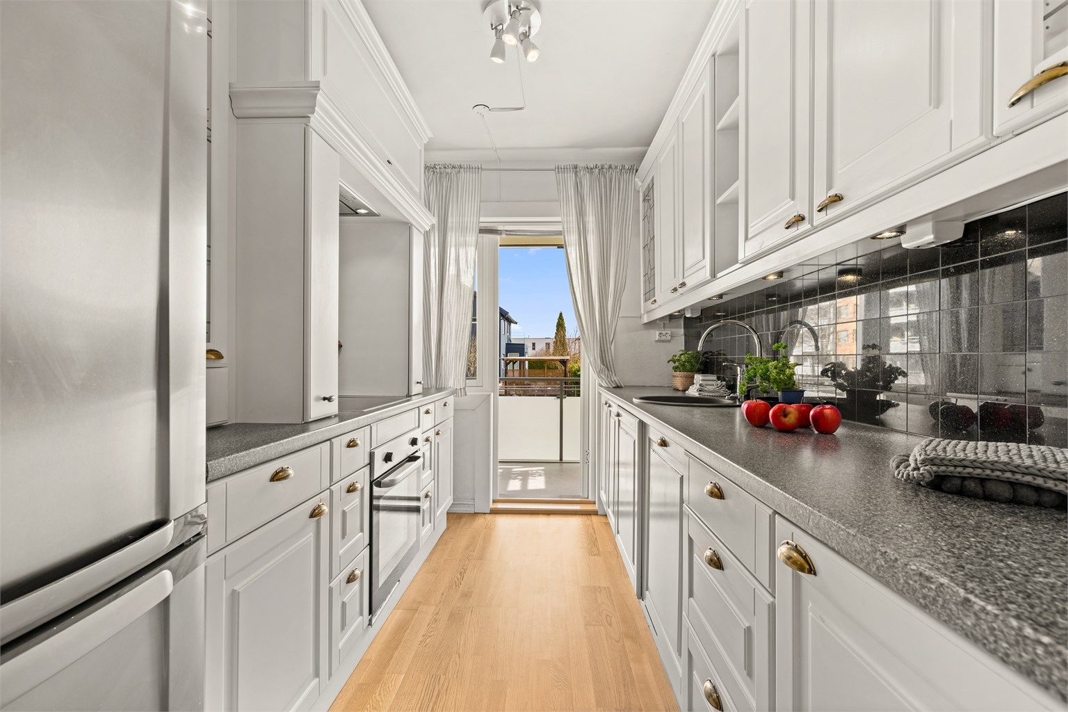 Funksjonelt kjøkken med integrerte hvitevarer og direkte utgang til en av leilighetens to balkonger.