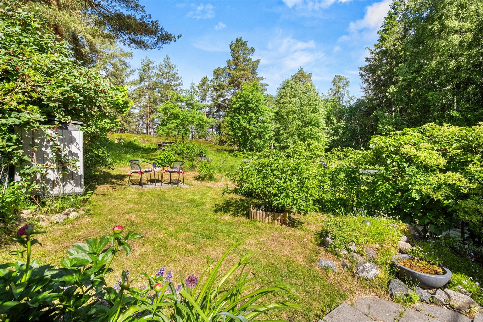 Eiertomten på 160 m² er opparbeidet med belegningsstein, terrasse på terreng, plenarealer og diverse beplantning.