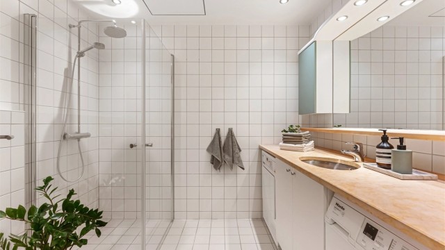 Flislagt baderom med gulvvarme, downlights, regndusj og opplegg for vaskemaskin.