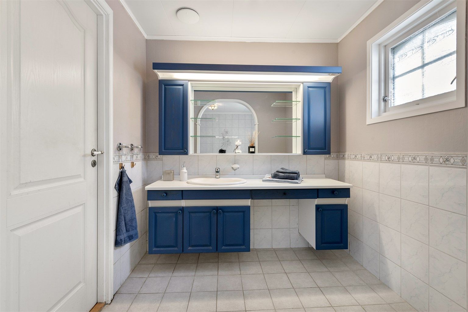 Innredningen på badet har en bred benkeflate med servant og god oppbevaringsplass i underskap.