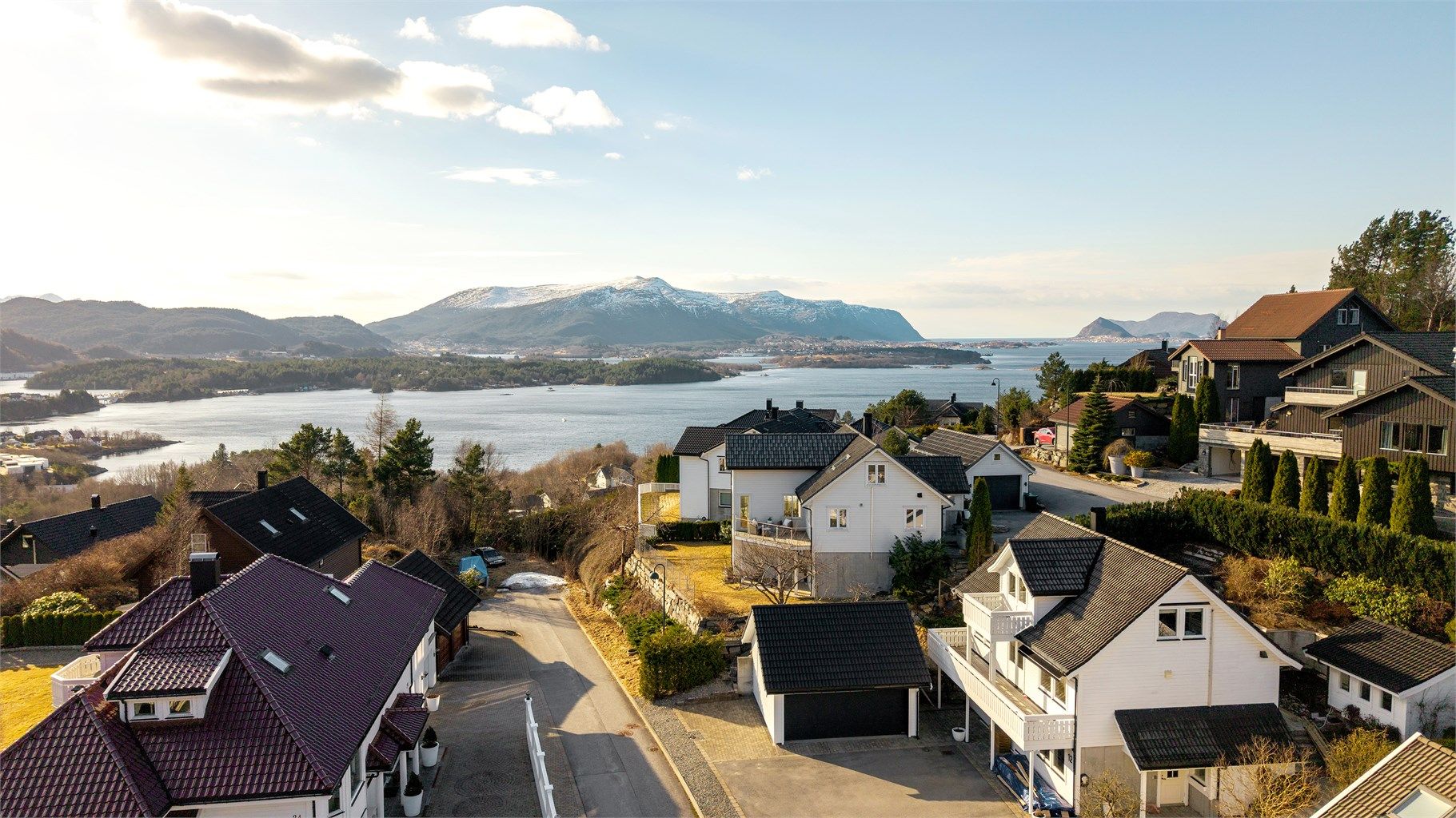 Dronebilde av eiendommen og nærområdet.  Bildet er tatt fra øst mot vest