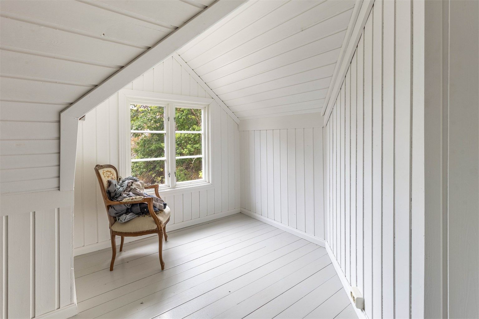 Loftsetasjen har et klassisk eldre uttrykk med lyst treverk på vegger, tak og gulv.