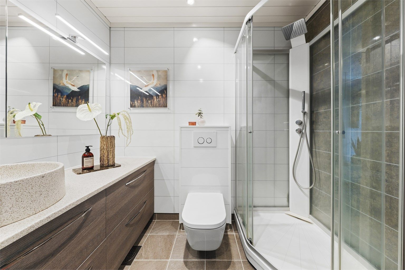 Badet er innredet med vegghengt toalett, ovenpåliggende servant med armaturer, samt opplegg for vaskemaskin.