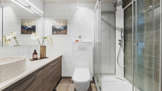 Badet er innredet med vegghengt toalett, ovenpåliggende servant med armaturer, samt opplegg for vaskemaskin.