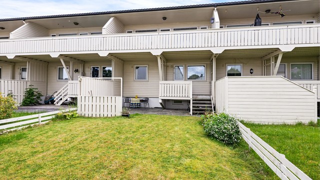 Boligens bakside med hage og to uteplasser i høyden.